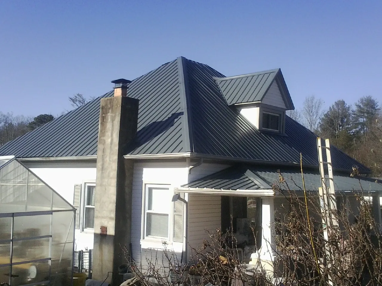 Dark blue standing seam metal roof on a white farmhouse with dormer — Slate & Tile Roof Repair by Roofing Brothers in Pecatonica