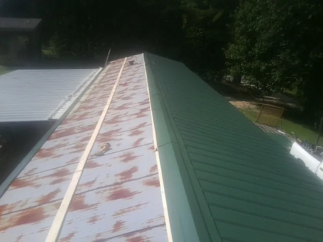 Old rusted panels beside newly installed green metal roofing — Wind Damage Roof Repair by Roofing Brothers in Pecatonica