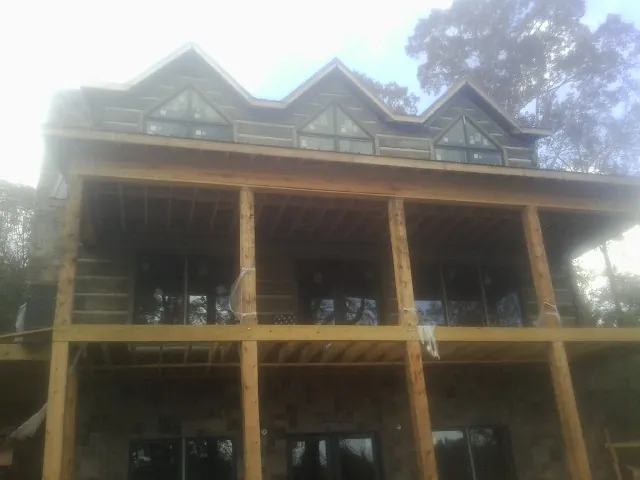 Dormers and porch framing on a large log home under construction — Roof Coating work by our crew in Pecatonica