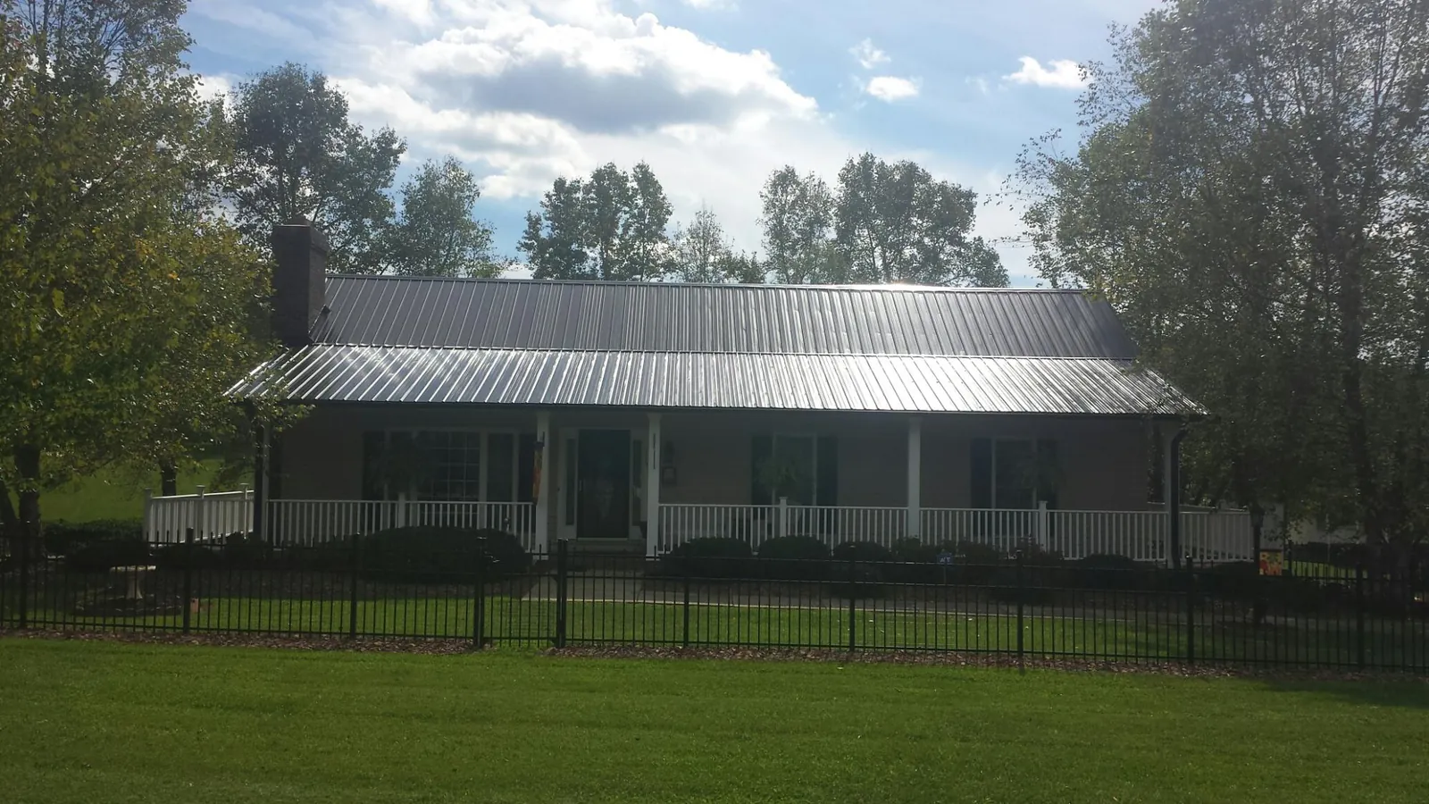 Gray metal roof on a brick ranch with a full width front porch — Gutter Guard Installation work by our crew in Pecatonica
