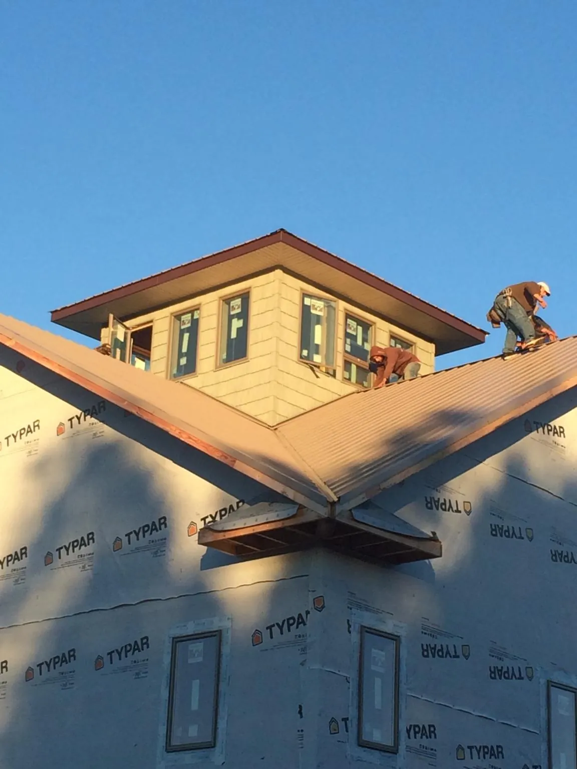 Roofers working around a rooftop cupola on a new metal roof at sunset — Roof Waterproofing in Pecatonica by Roofing Brothers